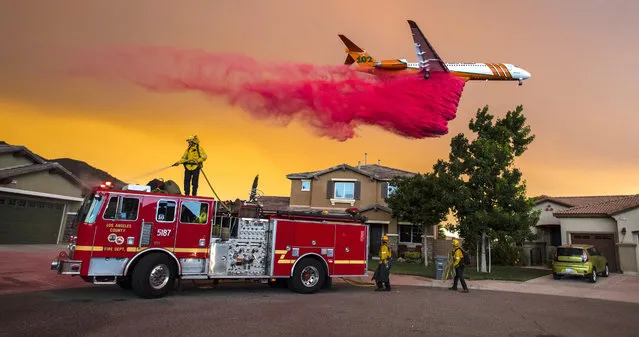 A plane drops fire retardant behind homes along McVicker Canyon Park Road in Lake Elsinore, Calif., as the Holy Fire burned near homes on Wednesday, August 8, 2018. (Photo by Mark Rightmire/The Orange County Register via AP Photo)