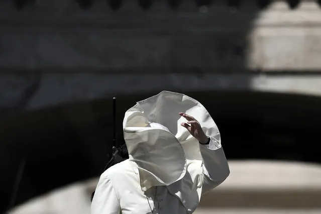 A gust of wind blows the mantle of Pope Francis as he blesses the faithfuls after a mass to the italian youths at St. Peter's square in the Vatican, on August 12, 2018. (Photo by Filippo Monteforte/AFP Photo)