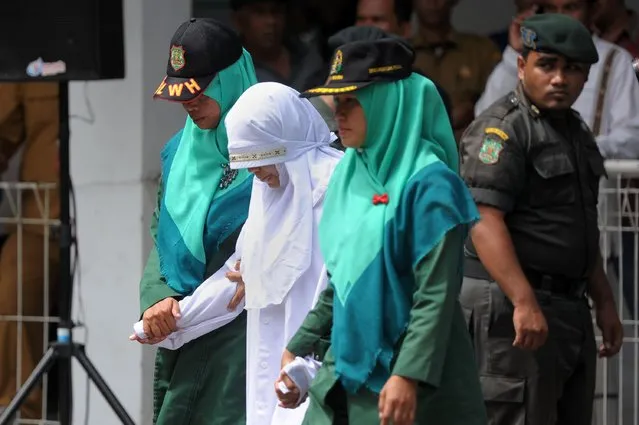 Acehnese sharia policewomen guard a woman (in white) who will receive 100 lashes of the cane for having s*x outside marraige, which is against sharia law, in Banda Aceh on November 28, 2016. Aceh is the only province in the world's most populous Muslim-majority country that imposes sharia law. People can face floggings for a range of offences – from gambling, to drinking alcohol, to gay s*x. (Photo by Chaideer Mahyuddin/AFP Photo)