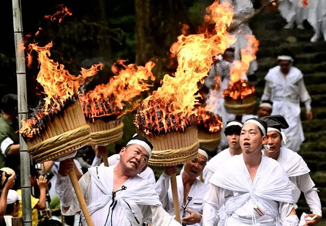 Shrine parishioners hold big flaming torches to purify the path for portable shrines during Kumano Nachi Fire Festival on July 14, 2023 in Nachikatsuura, Wakayama, Japan. The festival, held on July 14 every year, originated 1,500 years ago (Photo by The Asahi Shimbun via Getty Images)