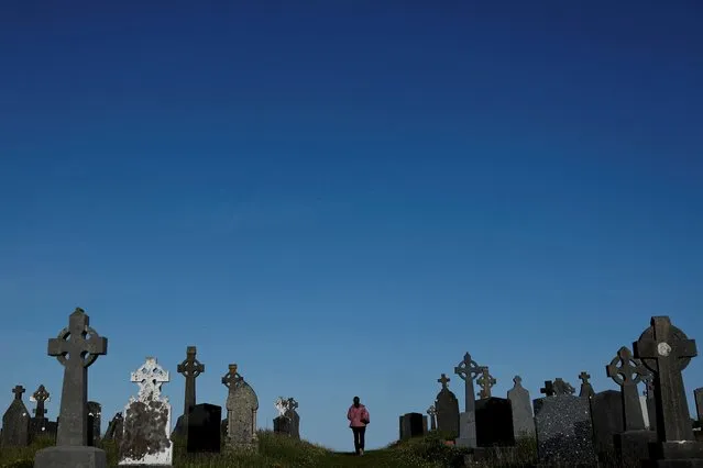 A woman walks through a graveyard, in the County Galway village of Furbo, Ireland on May 16, 2023. (Photo by Clodagh Kilcoyne/Reuters)