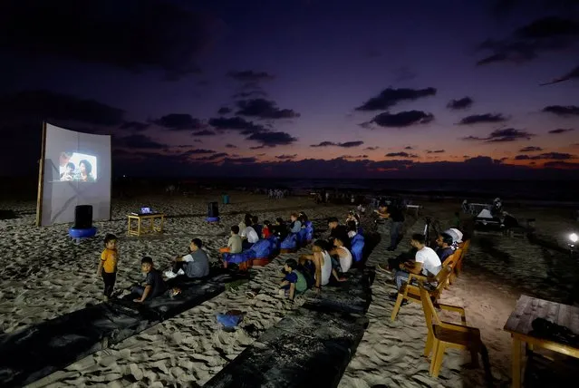 Palestinian families watch a large projector screen at a beachfront cafe during a rare cinema event, in Gaza City on August 11, 2023. (Photo by Mohammed Salem/Reuters)