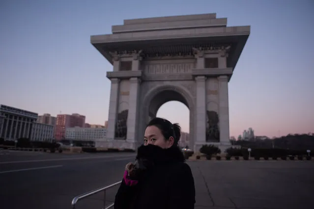 A tour guide shields her face from the cold as she stands before the Arch of Triumph in Pyongyang on December 1, 2016. (Photo by Ed Jones/AFP Photo)