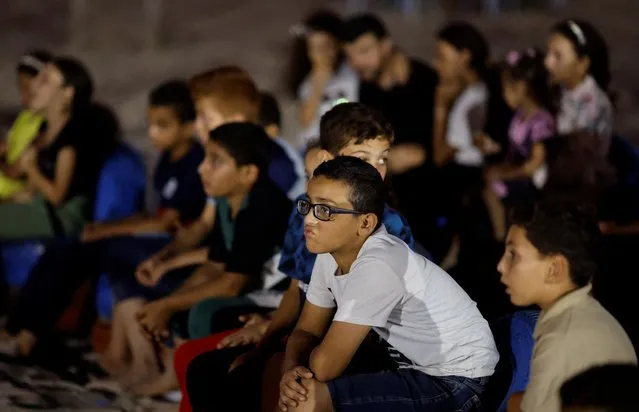 Palestinian families watch a large projector screen at a beachfront cafe during a rare cinema event, in Gaza City on August 11, 2023. (Photo by Mohammed Salem/Reuters)