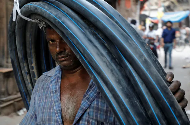 A man carries pipes on his head through a street in the old quarters of Delhi, India, October 1, 2018. (Photo by Anushree Fadnavis/Reuters)