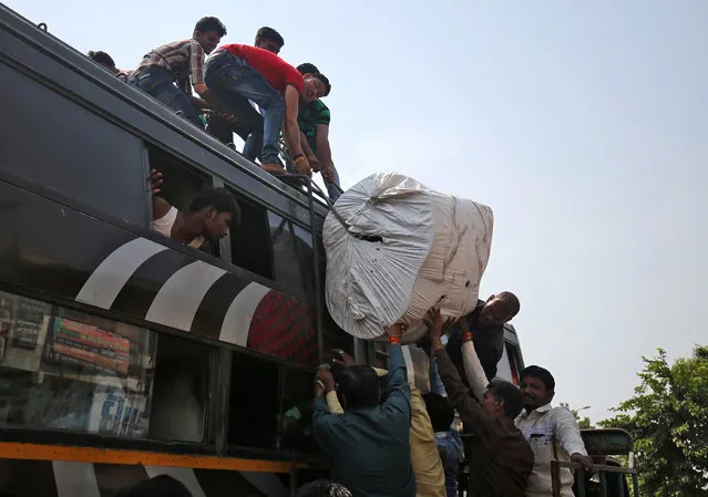 Migrant workers from Madhya Pradesh and Uttar Pradesh load their luggage on the roof of a bus as they prepare to depart, in Ahmedabad, October 10, 2018. (Photo by Amit Dave/Reuters)