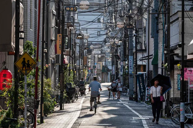 People navigate along a street in the Minami-Senju area of Arakawa Ward in Tokyo on September 12, 2023. (Photo by Richard A. Brooks/AFP Photo)