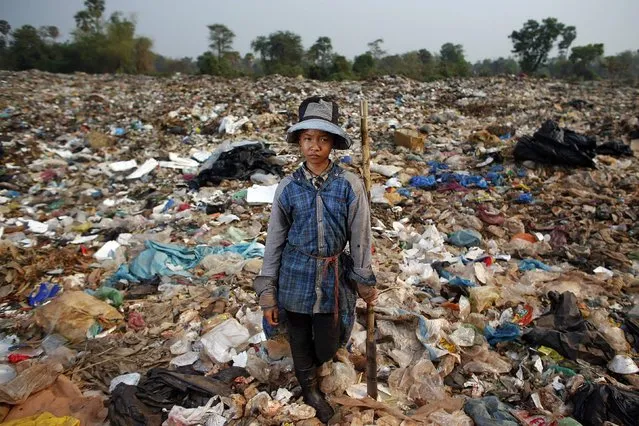 Saven, a 14-year-old girl, poses for a picture while collecting usable items at landfill dumpsite outside Siem Reap March 19, 2015. Saven, who finished six-grade primary school and did not continue education because of poverty, earns 1.25 USD per day working at the dumpsite so her three younger brothers can go to school. (Photo by Athit Perawongmetha/Reuters)