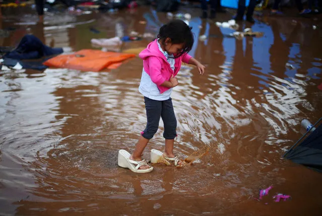 Rosa Julia Romero, a four-year-old migrant girl from Honduras, part of a caravan of thousands from Central America trying to reach the United States, wears her mother's shoes as she walks through a temporary shelter after heavy rainfall in Tijuana, Mexico, November 29, 2018. (Photo by Hannah McKay/Reuters)