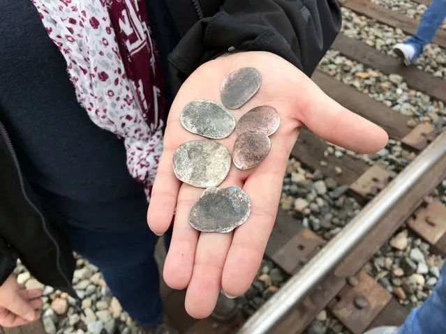 Ana Garza, of Cypress, Texas, displays coins flattened by the memorial train carrying the casket of President George H.W. Bush when it passed through Pinehurst, Texas, Thursday, December 6, 2018. On Thursday, that same 4,300-horsepower machine left a suburban Houston railyard loaded with Bush's casket for his final journey after almost a week of ceremonies in Washington and Texas. (Photo by Nomaan Merchant/AP Photo)