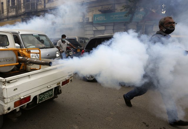 Volunteers on a vehicle spray to disinfect market area in an effort to contain the outbreak of the coronavirus, in Karachi, Pakistan, Monday, August 2, 2021. (Photo by Fareed Khan/AP Photo)