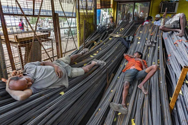 Workers who transport iron rods used in building construction take a break at a warehouse in Prayagraj, India, Thursday, July 29, 2021. (Photo by Rajesh Kumar Singh/AP Photo)
