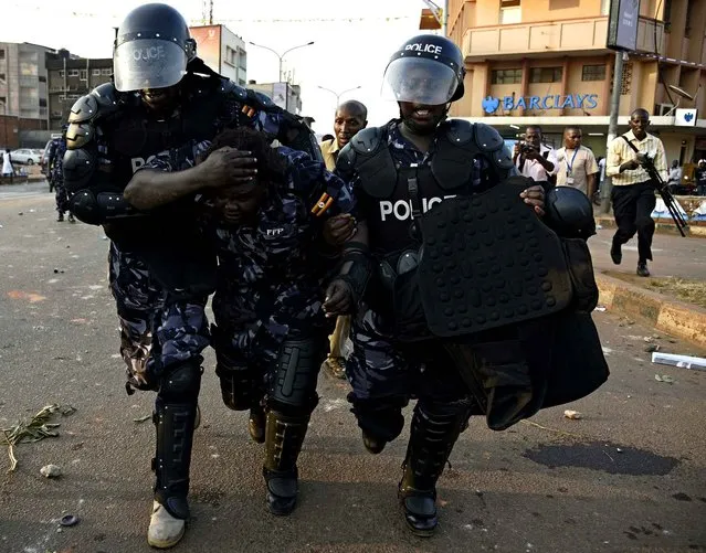 Ugandan female police officer is rushed away from supporters after she was hit by a tear gas cannister thrown back at the police line by protesting supporters of opposition leader Kizza Besigye in Kampala on February 15, 2016, two days before the Uganda's Presidential elections. Besigye was today arrested and denied access to his rally at Makerere university. Incumbent President Museveni is facing the hardest fight to keep his office as his main rival Kizza Besigye and his former Prime Minister Amama Mbabazi have gained country wide support. (Photo by Isaac Kasamani/AFP Photo)