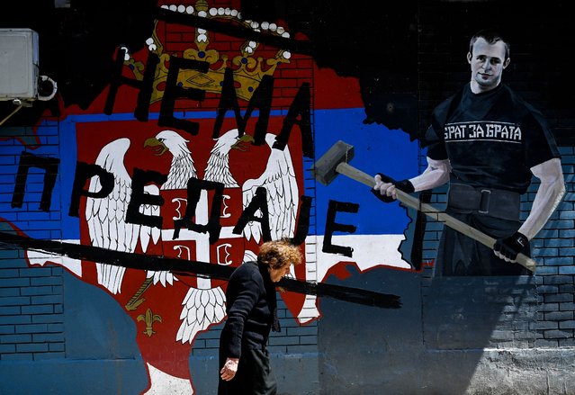 A Kosovo Serb woman walks past a graffiti showing the Serbian flag and reading as “There's no giving up”, on a street in the majority ethnic-Serb northern part of the city of Mitrovica, on June 15, 2021. The leaders of Serbia and Kosovo are in Brussels on June 15, 2021, to resume EU-mediated talks aimed at finding a solution to one of Europe's most intractable territorial disputes. (Photo by Armend Nimani/AFP Photo)