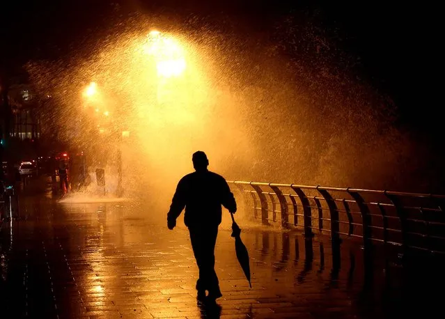 A man walks in front of high waves crashing on the seafront in Beirut, Lebanon, on December 11, 2013. Lebanon is under the effects of a blustery storm, dubbed Alexa, that dropped torrential rain and snow and pushed temperatures below freezing in northern Lebanon and some areas of the Bekaa Valley, which is dotted with informal Syrian refugee settlements. (Photo by Hussein Malla/Associated Press)