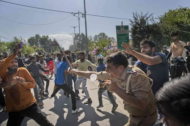An Indian policemen is shielded by a Kashmiri Shiite Muslim, right, while others attack him during a religious procession in central Srinagar, Indian controlled Kashmir, Tuesday, August 17, 2021. Police in Indian-controlled Kashmir on Tuesday fired tear gas and warning shots to disperse hundreds of Shiite Muslims, while detaining dozens who attempted to participate in processions marking the Muslim month of Muharram. (Photo by Dar Yasin/AP Photo)