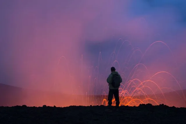 A tourist stands on the edge of the fountain of lava. (Photo by Denis Budkov/Caters News)