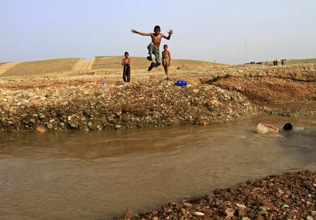 An Afghan boy jumps into a muddy body of water as he goes for a swim with his friends on the outskirts of Jalalabad April 16, 2015. (Photo by Reuters/Parwiz)