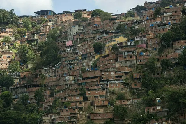 This February 14, 2019 photo shows a portion of the Petare shanty town, one of Latin America's largest slums, in Caracas, Venezuela. Some 400,000 people live crowded into the thousands of brightly colored cinderblock homes that blanket the Caracas hillsides as far as the eye can see. (Photo by Rodrigo Abd/AP Photo)