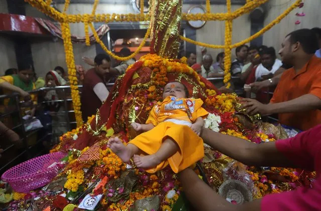 A priest holds a baby boy as they seek blessings for him inside the temple of Goddess Alopi Devi during Navratri festival in Prayagraj, April 6, 2019. (Photo by Jitendra Prakash/Reuters)