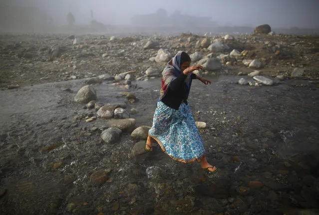 A women jump to reach a rock as she crosses Chepay River at Sapay, Achham in the Far-Western region of Nepal, around 900 km (559 miles) from Kathmandu February 17, 2014. (Photo by Navesh Chitrakar/Reuters)