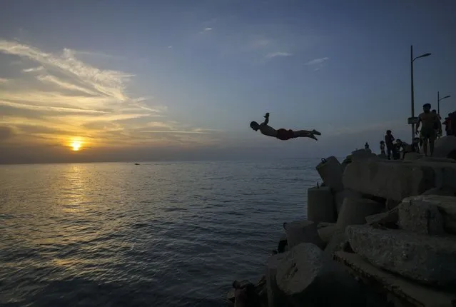 Palestinians jump into the Mediterranean Sea on October 29, 2021 in Gaza City. (Photo by Mahmud Hams/AFP Photo)