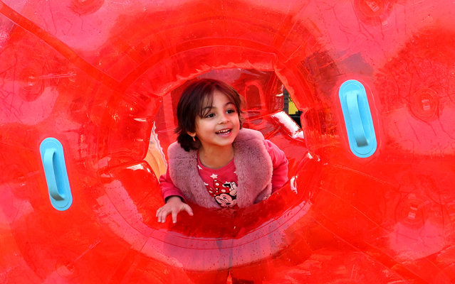 A young girl looks from behind an inflatable floater at the “Ab-o-Atash” (Water-and-Fire) amusement park in the north of Iran's capital Tehran on November 14, 2021. (Photo by Atta Kenare/AFP Photo)