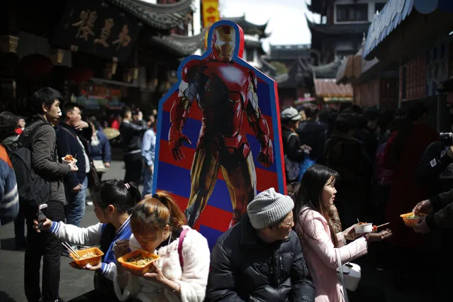 Tourists eat lunch under a cutout of fictional superhero Iron Man in Yuyuan Garden in Shanghai, China, March 15, 2016. (Photo by Aly Song/Reuters)