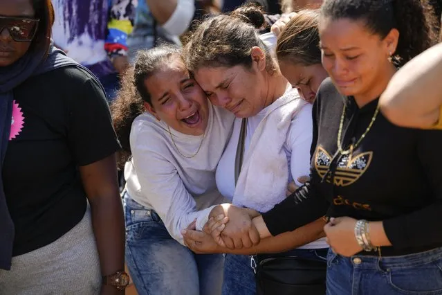 A sister of miner Santiago Mora, left, cries with other relatives as he is buried at the cemetery in La Paragua, Bolivar state, Venezuela, Thursday, February 22, 2024. The collapse of an illegally operated open-pit gold mine in central Venezuela killed at least 14 people and injured several more, state authorities said Wednesday, as some other officials reported an undetermined number of people could be trapped. (Photo by Ariana Cubillos/AP Photo)