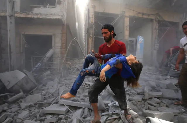 A man evacuates a young bombing casualty after a reported air strike by regime forces and their allies in the jihadist-held Syrian town of Maaret Al-Noman in the southern Idlib province, on May 26, 2019. Regime air strikes killed 12 civilians including four at a market today in a jihadist bastion in northwest Syria, a war monitor said. (Photo by Abd el-Aziz Qitaz/AFP Photo)