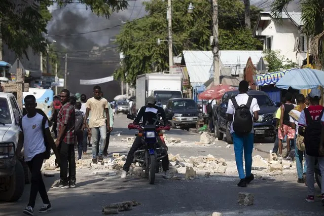 A moto-taxi rides through a barricade of rocks set up by friends and relatives of James Philistin who was kidnapped last night, in Port-au-Prince, Haiti, Wednesday, November 24, 2021. (Photo by Joseph Odelyn/AP Photo)