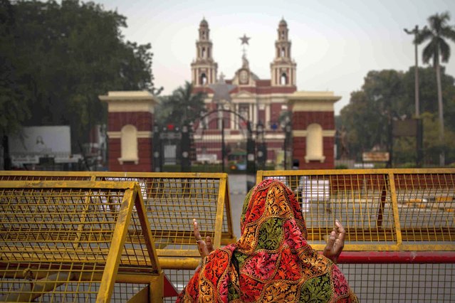 An Indian woman prays in front of a police barricade near the gate of Sacred Heart Cathedral which is closed to general public due to COVID-19 restrictions on the eve of Christmas in New Delhi, India, Friday, December 24, 2021. (Photo by Altaf Qadri/AP Photo)