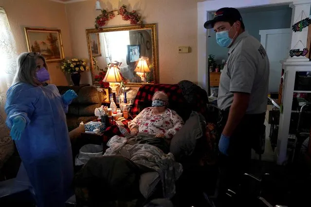 A REACT EMS paramedic talks with a home health nurse in the home of an 82 year old woman suffering from possible coronavirus disease (COVID-19) symptoms after she was exposed to a COVID-19 positive family member in Shawnee, Oklahoma, U.S. January 12, 2022. (Photo by Nick Oxford/Reuters)