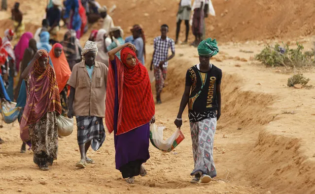 In this photo taken Wednesday, March 8, 2017, women and men carry away earth after digging to build a dam so that if rains do come the water can be stored near Bandar Beyla in Somalia's semiautonomous northeastern state of Puntland. (Photo by Ben Curtis/AP Photo)