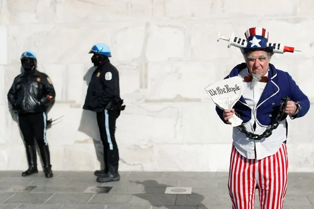 A man wearing a costume poses next to police officers at the Lincoln Memorial during the anti-vaccine mandate march in Washington, D.C., U.S., January 23, 2022. (Photo by Tom Brenner/Reuters)