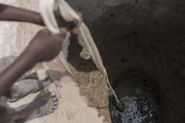 In this photo taken Sunday, March 12, 2017, a girl Abuk gathers dirty water from an old well in her village in Aweil, in South Sudan. (Photo by Mackenzie Knowles-Coursin/UNICEF via AP Photo)