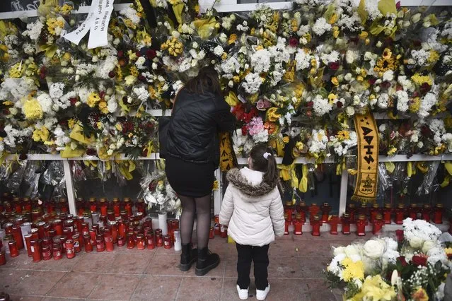 A woman places flower at the scene where a teenager was killed and two others injured after being stabbed outside the Aris FC stadium, in the northern port city of Thessaloniki, Greece, on Monday, February 7, 2022. The victim was a fan of soccer club Aris, and his attackers were allegedly supporters of rival PAOK. Authorities in Greece have promised to toughen rules governing soccer supporters' associations in the wake of a deadly attack last week the left a 19-year-old man dead after he was stabbed and severely beaten in the northern city of Thessaloniki. (Photo by Giannis Papanikos/AP Photo)