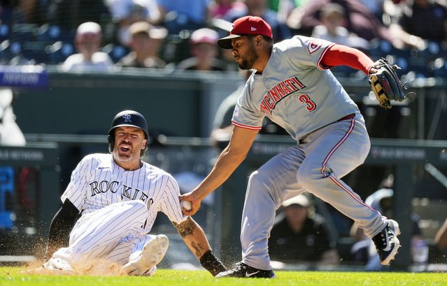 Cincinnati Reds third baseman Jeimer Candelario, right, tags out Colorado Rockies' Jake Cave after he was caught in a rundown between third base and home plate in the eighth inning of a baseball game Wednesday, June 5, 2024, in Denver. (Photo by David Zalubowski/AP Photo)