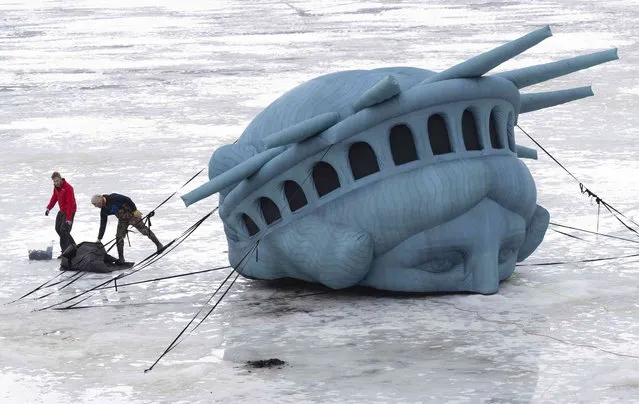A pair of workers finish setting up the crown part of a Statue of Liberty replica Friday, February 11, 2022, near the University of Wisconsin Memorial Union on Lake Mendota in Madison, Wis. Because of temperatures in the mid-40s, it was decided not to erect the torch part of the illusion. The inflatable replica, is part of the Wisconsin Union's Winter Carnival that runs through Saturday. The original Styrofoam version first appeared on Lake Mendota in 1979 as a prank by the Pail and Shovel Party, which was led by UW-Madison alumni Leon Varjian and Jim Mallon. It was destroyed by an arsonist. (Photo by Mark Hoffman/Milwaukee Journal-Sentinel via AP Photo)