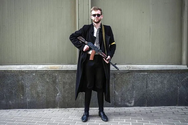 Svyatoslav Yurash, 26, a lawmaker from Zelensky's Servant of the People party, poses with his assault rifle as he patrols downtown Kyiv on February 27, 2022. (Photo by Aris Messinis/AFP Photo)