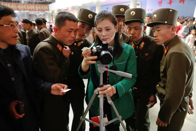 Soldiers check their souvenir photo as they visit the flower exhibition marking the 105th birth anniversary of the country's founding father, Kim Il Sung in Pyongyang, North Korea April 16, 2017. (Photo by Damir Sagolj/Reuters)