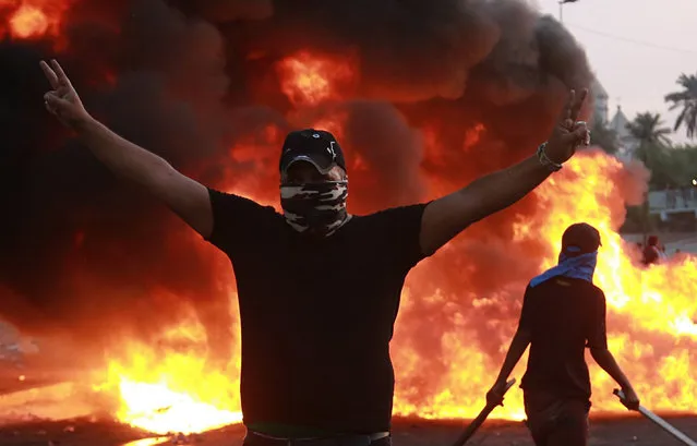 An anti-government protester flashes the victory sign during a demonstration in Baghdad, Iraq, Thursday, October 3, 2019. Iraqi security forces fired live bullets into the air and used tear gas against a few hundred protesters in central Baghdad on Thursday, hours after a curfew was announced in the Iraqi capital on the heels of two days of deadly violence that gripped the country amid anti-government protests that killed several people in two days. (Photo by Hadi Mizban/AP Photo)