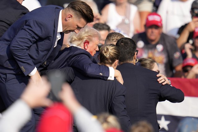 Republican presidential candidate former President Donald Trump is helped off the stage at a campaign event in Butler, Pa., on Saturday, July 13, 2024. (Photo by Gene J. Puskar/AP Photo)