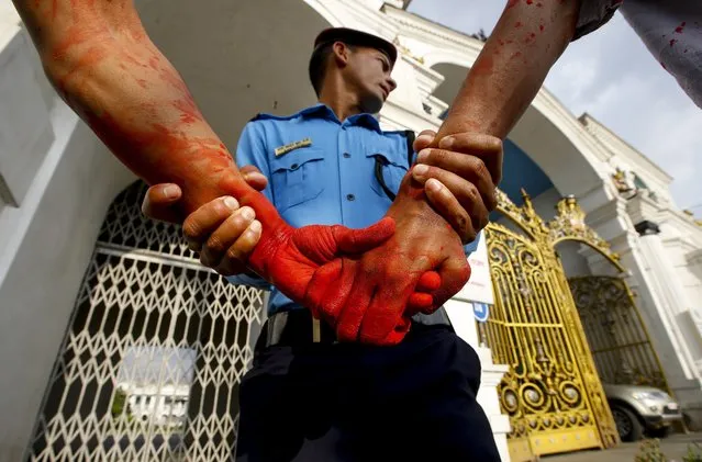 Nepalese Police arrest some youths social activist after they threw a red color paint across the main entrance of the Singhdurbar, a main government complex, in Kathmandu, Nepal, 26 May 2016. Group of youths painting their face with red color threw red paint at the main entrance of government complex demanding the government to address the issues of Ethnic Madhesi and other minority groups. Nepals Ethnic Madhesi  and other indigenous communities are in a protests against the new constitution, demanding more political representation for ethnic minorities in the nation's parliament. (Photo by Narendra Shrestha/EPA)