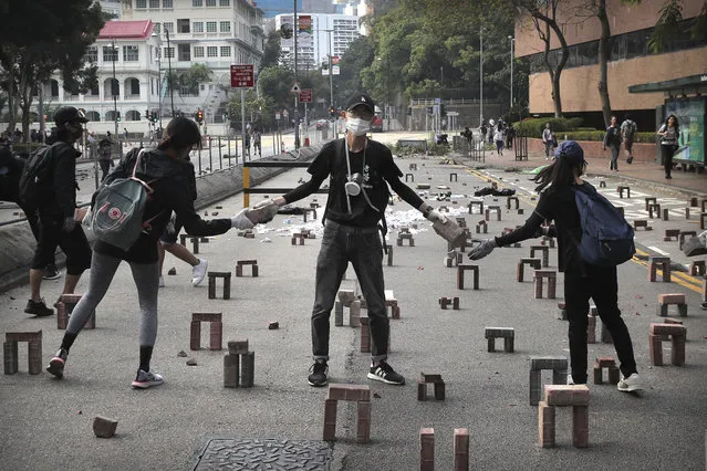 In this Thursday, November 14, 2019, file photo, protesters move bricks as they barricade a road near the Hong Kong Polytechnic University in Hong Kong. Protesters who barricaded themselves inside Hong Kong’s universities have tried to turn the campuses into armed camps, resorting to medieval weapons to stop police from entering the grounds. Their weapons include bows and arrows, catapults and hundreds of gasoline bombs stacked up to ramparts – often built by the students. (Photo by Kin Cheung/AP Photo/File)