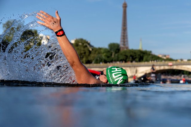 Hungary's Kristof Rasovszky backstrokes while taking a drink in the feeding station during the men's 10km marathon swimming final at the Paris 2024 Olympic Games at Pont Alexandre III in Paris on August 9, 2024. (Photo by David Goldman/AFP Photo)