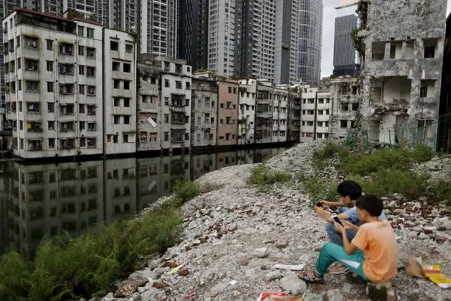 People play with their phones on wreckage of houses in Xian village, a slum area in downtown Guangzhou, China July 24, 2015. (Photo by Tyrone Siu/Reuters)