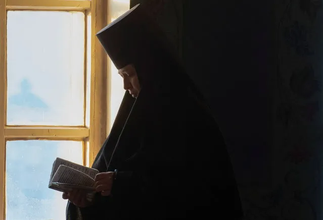 A nun reads a prayer book during the Orthodox Christmas service at Saint Nicholas convent in the settlement of Mogochino in the Tomsk region, Russia January 7, 2022. (Photo by Taisiya Vorontsova/Reuters)