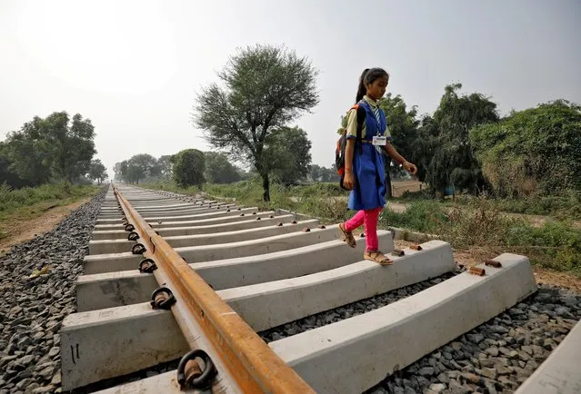 A schoolgirl walks on an under-construction railway track at Navapura, on the outskirts of Ahmedabad, November 29, 2019. (Photo by Amit Dave/Reuters)