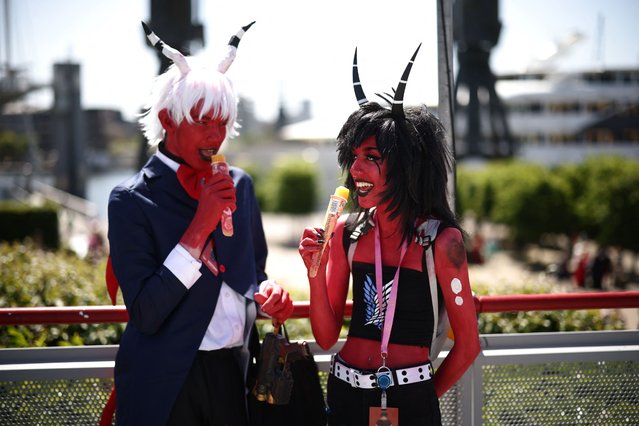 Cosplayers enjoy an ice cream in the sunshine outside MCM Comic Con at ExCeL exhibition centre in London on May 26, 2023. (Photo by Henry Nicholls/AFP Photo)